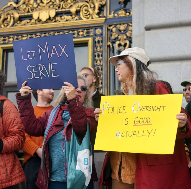 People at a protest hold signs reading "Let Max Serve" and "Police Oversight is Good Actually!" in front of an ornate building, demanding action from the police commission.