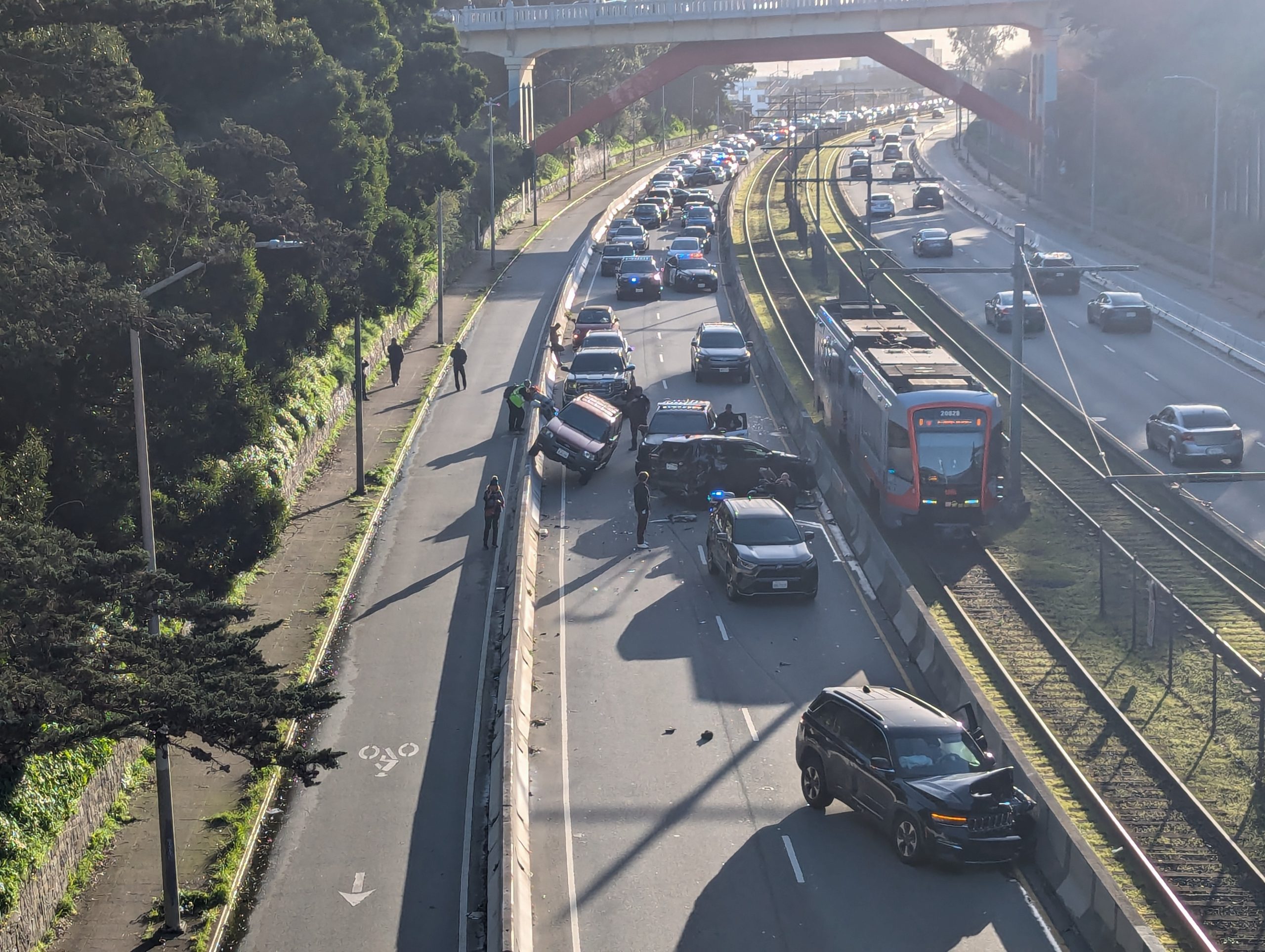 Multi-car accident on a highway with several vehicles involved, emergency response team on site, and light traffic build-up in the background.