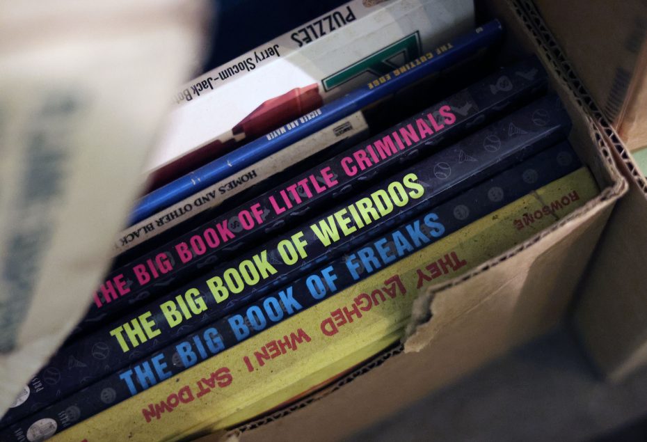A box containing books with colorful spines, titled "The Big Book of Little Criminals," "The Big Book of Weirdos," "The Big Book of Freaks," and "They Laughed When I Sat Down.