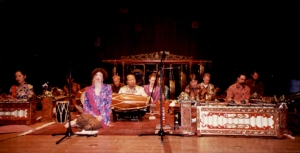 A group of musicians in traditional attire playing gamelan instruments on a stage.