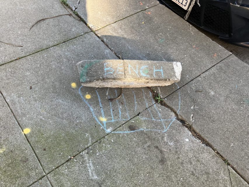 Concrete block labeled "BENCH" on sidewalk with chalk drawn seat outline.