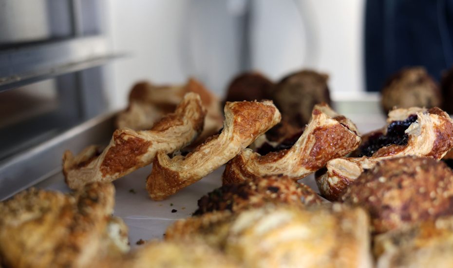 A tray of assorted pastries, including croissants and danishes, displayed in a bakery setting.