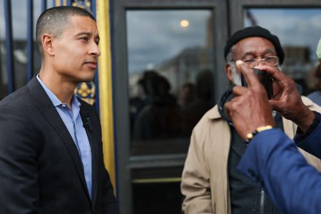 Two men stand outside a building with ornate details; one faces the camera while the other, channeling his inner Carter-Oberstone, captures the moment with a smartphone. Max Carter-Oberstone on the left.