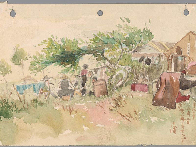 A group of people gather under a tree near a tent, with clothes hanging on a line and grassy vegetation in the foreground.