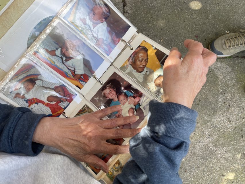 Hands flipping through a photo album with various family photographs.