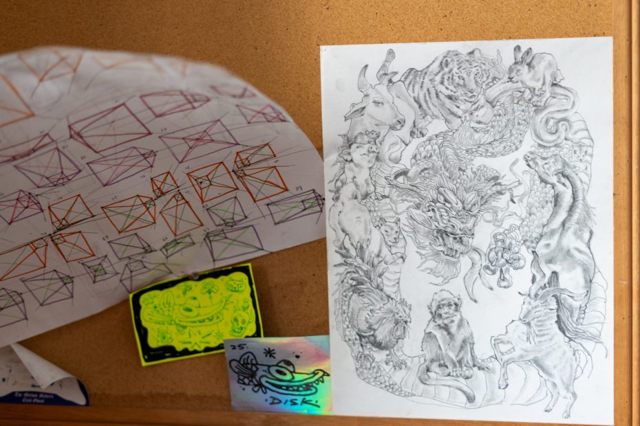 Bulletin board with geometric sketches and a detailed animal illustration, featuring a tiger, dragon, monkey, among others. A neon green note and small holographic sticker are also visible.