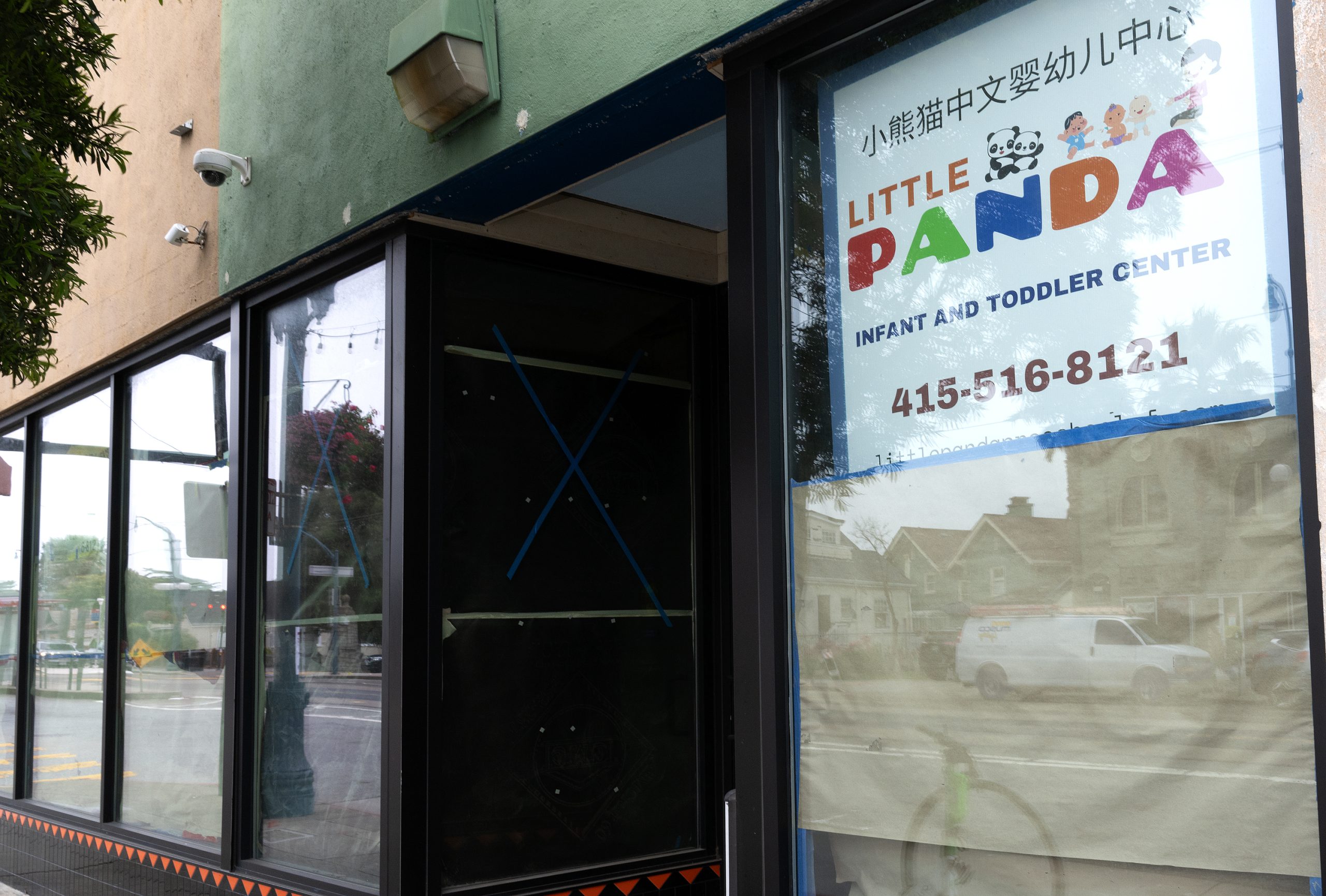 Storefront with a sign reading "Little Panda Infant and Toddler Center" along with a phone number; windows reflect the street outside.