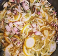 Sliced lemons and pink flower petals are soaking in liquid, possibly for an infusion or homemade syrup preparation.