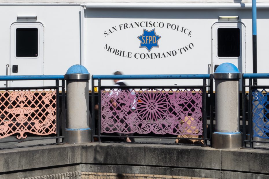 A San Francisco Police Mobile Command vehicle is seen behind a decorative fence with pink and purple panels.