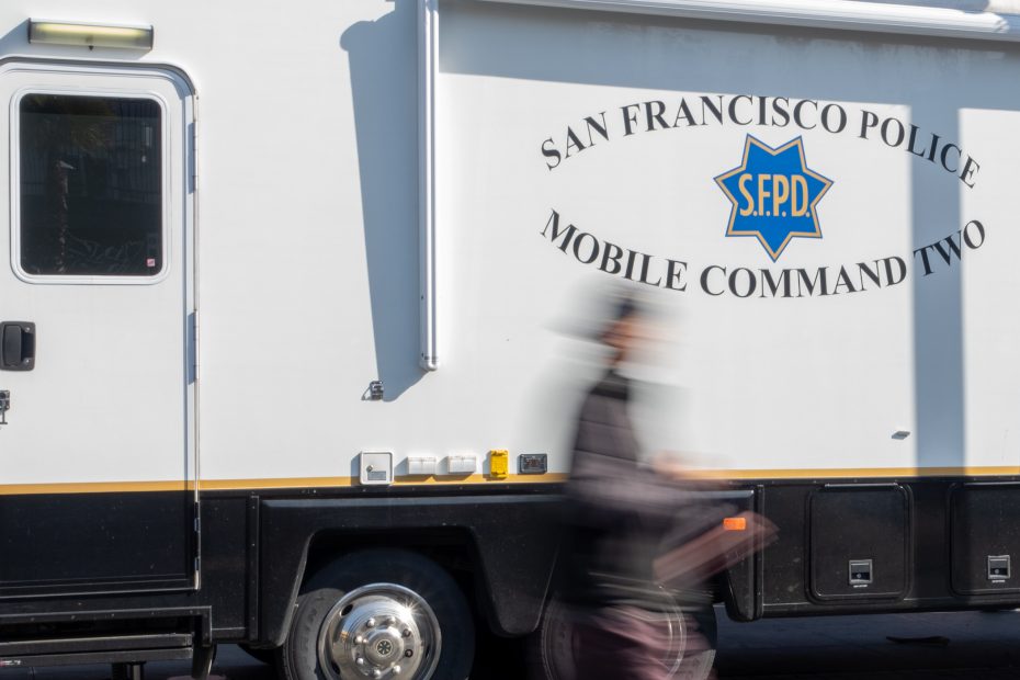 A person walks by a parked San Francisco Police Mobile Command vehicle with the logo and "Mobile Command Two" text visible.