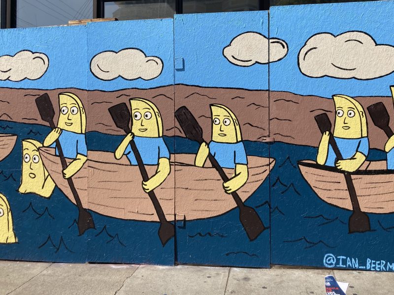 Colorful mural depicting cartoon characters in blue shirts rowing boats on a river with clouds above.