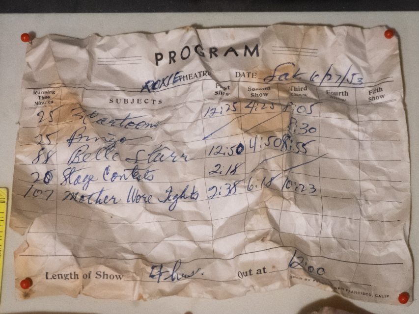 A crumpled paper program lists show subjects, times, and notes in blue ink for an event dated Sat 6/17/13, pinned to a board with red thumbtacks.