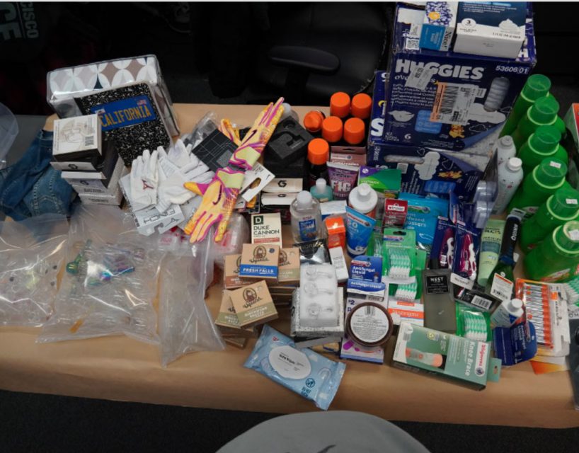A table covered with various household items, including diapers, cleaning products, gloves, toothbrushes, and toothpaste, arranged in an organized manner.