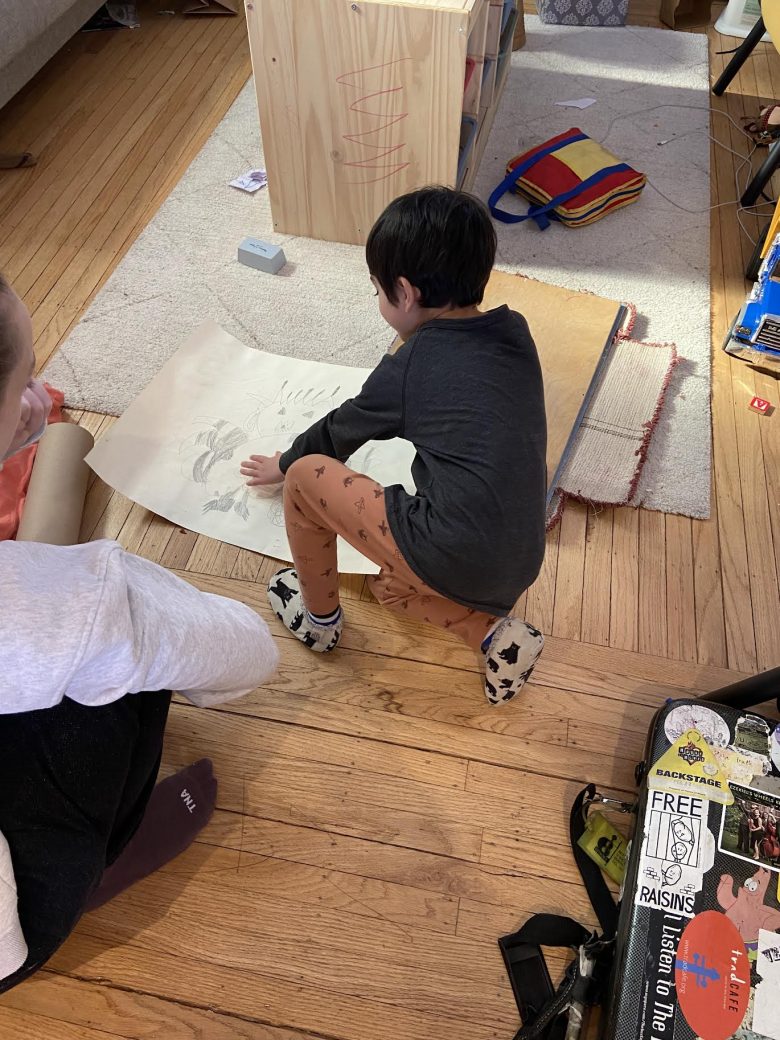 Sara Mann looks at the mixed media collage, “Asteroid Eaters in Space,” that she created with her five-year-old son, Ezra, and ponders the state of the earth. Ezra keeps his mom earthbound. Asteroid eaters, according to Ezra, are protectors of the earth.