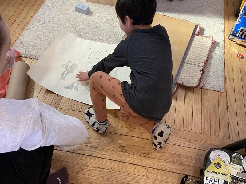 Sara Mann looks at the mixed media collage, “Asteroid Eaters in Space,” that she created with her five-year-old son, Ezra, and ponders the state of the earth. Ezra keeps his mom earthbound. Asteroid eaters, according to Ezra, are protectors of the earth.