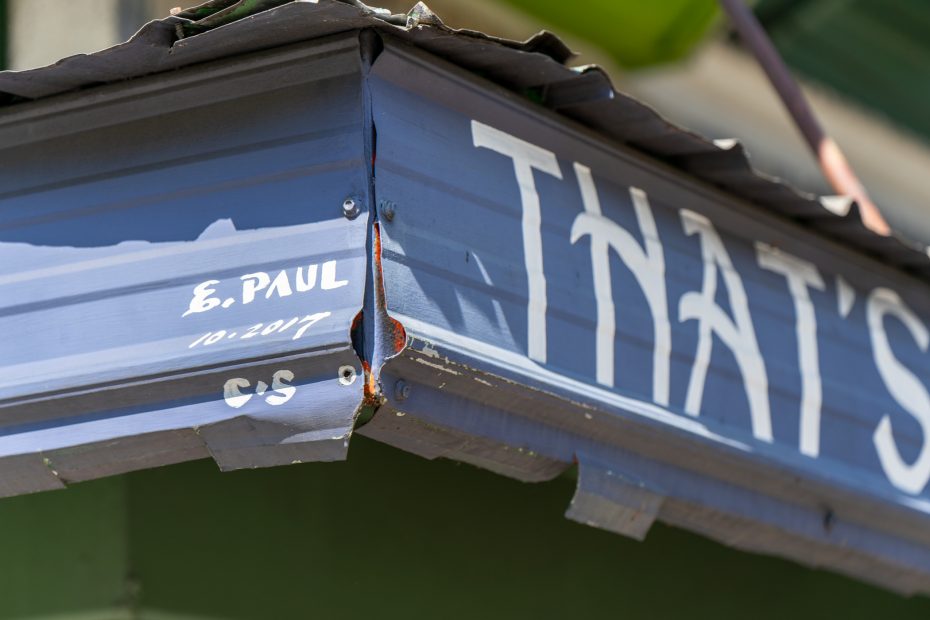 Close-up of a blue corrugated metal awning with partial white text, handwritten signature "E. Paul 10/2017," and the initials "C/S" visible.