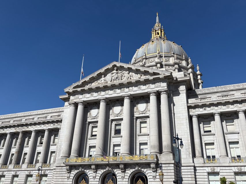 A neoclassical building with tall columns, ornate carvings, and a large dome topped with a gilded structure against a clear blue sky.
