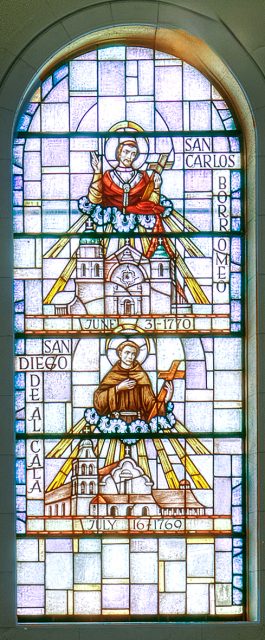 Stained glass window depicts San Carlos Borromeo and San Diego de Alcalá above their respective mission churches with inscriptions and dates.