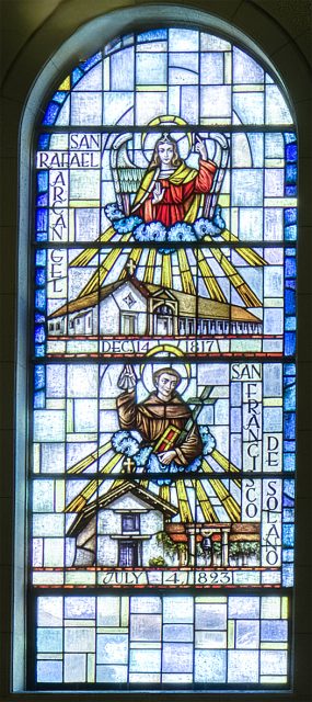 Stained glass window depicting San Rafael Arcangel above a mission church, and San Francisco Solano above another mission, with dates and names inscribed beside each scene.