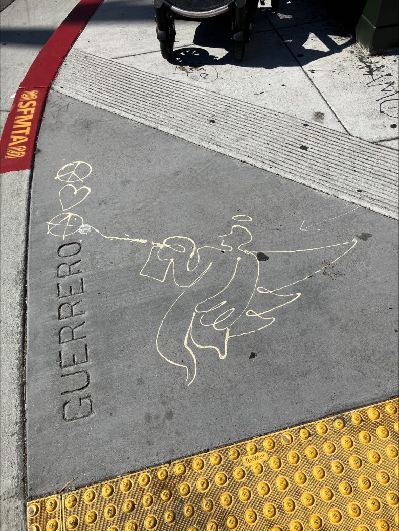 A chalk drawing of an angel spraying paint toward two hearts on a sidewalk near a yellow tactile paving and the word "GUERRERO" etched into the concrete.
