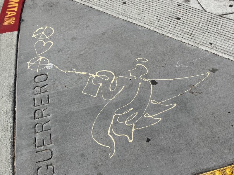 A chalk drawing of an angel spraying paint toward two hearts on a sidewalk near a yellow tactile paving and the word "GUERRERO" etched into the concrete.