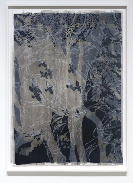 A museum-quality textile artwork depicts dark birds flying among abstract tree branches and foliage in shades of gray, blue, and beige.