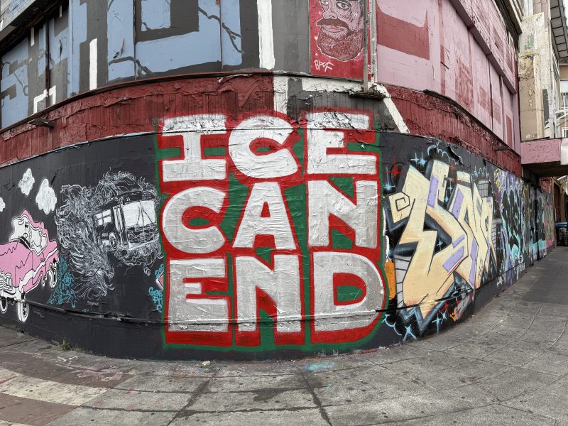 A street mural on a building corner reads "ICE CAN END" in bold red and white letters, surrounded by various colorful graffiti art.