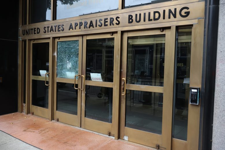 The entrance to the United States Appraisers Building with glass doors, brass frames, and a "Closed" sign visible inside.