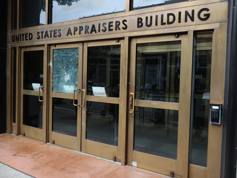 The entrance to the United States Appraisers Building with glass doors, brass frames, and a "Closed" sign visible inside.