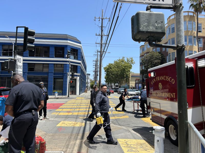 San Francisco Fire Department personnel respond to an emergency on a city street, with an ambulance and medical equipment visible.