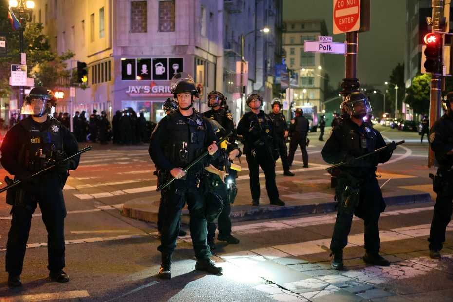 A group of police officers and ICE agents standing on a street.