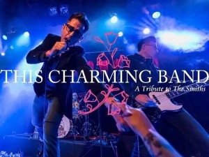 A band performs energetically on stage under blue lights, with text reading "This Charming Band: A Tribute to The Smiths" over the image.