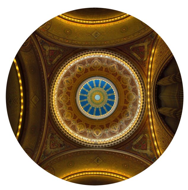 Ornate domed ceiling with intricate gold patterns, blue center, and illuminated details, viewed from directly below within a circular frame.