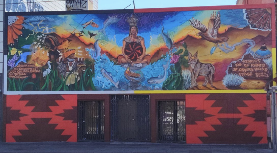 A colorful mural shows an Indigenous person meditating, surrounded by animals, plants, mountains, and text promoting respect for the rights of others in English and Spanish.