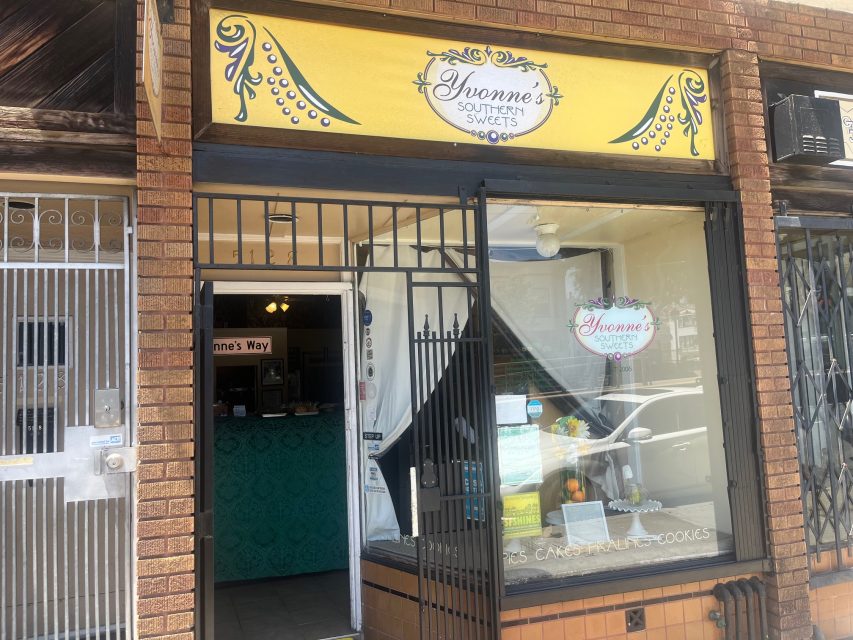 Storefront of "Yvonne's Southern Sweets" with a yellow sign above the door and window; interior counter and display case visible through open entrance.