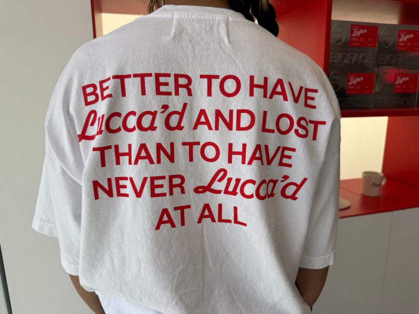 A person wearing a white T-shirt with red text that reads: "Better to have Lucca'd and lost than to have never Lucca'd at all.