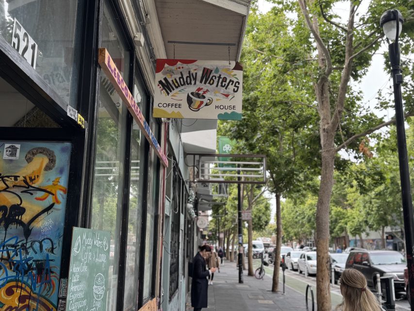 Street view of a sidewalk with a hanging sign for "Muddy Waters Coffee House," people walking, trees, and parked cars visible.