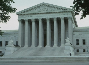 The front facade of the United States Supreme Court building, featuring large columns, steps, and statues on either side of the entrance.