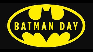 A yellow and black Batman logo with the words "BATMAN DAY" in yellow capital letters inside the bat symbol.
