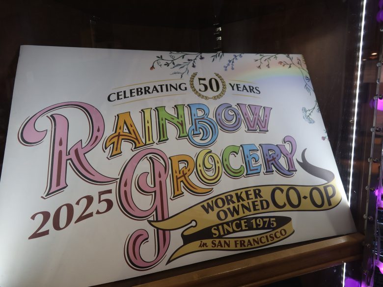Sign reading "Celebrating 50 Years, Rainbow Grocery, Worker Owned Co-op, Since 1975 in San Francisco, 2025" displayed with decorative text and rainbow colors.