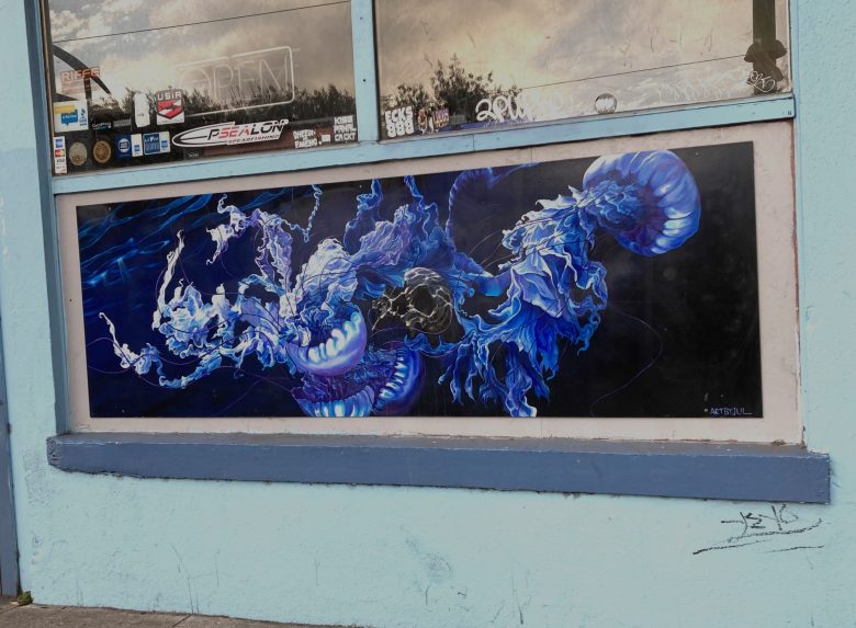 A mural on a wall depicts abstract, swirling blue and white forms resembling jellyfish against a black background.