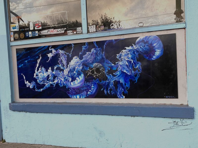 A mural on a wall depicts abstract, swirling blue and white forms resembling jellyfish against a black background.