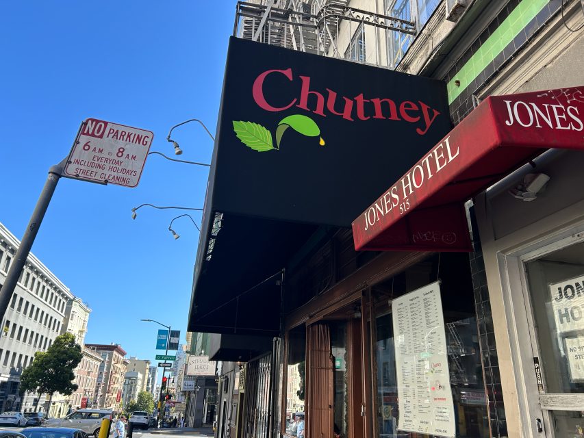 Street view of the Chutney restaurant sign next to Jones Hotel, with a no parking sign and buildings visible under a clear blue sky.