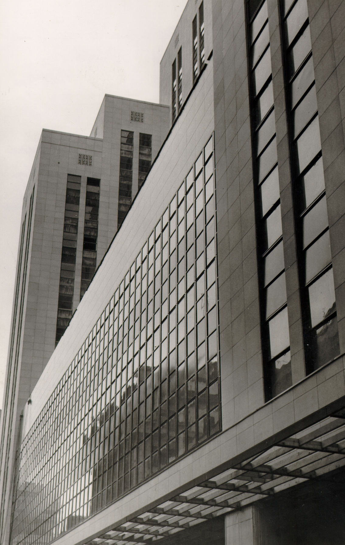 A modern multi-story office building with large glass windows and a geometric facade, photographed from a low angle.