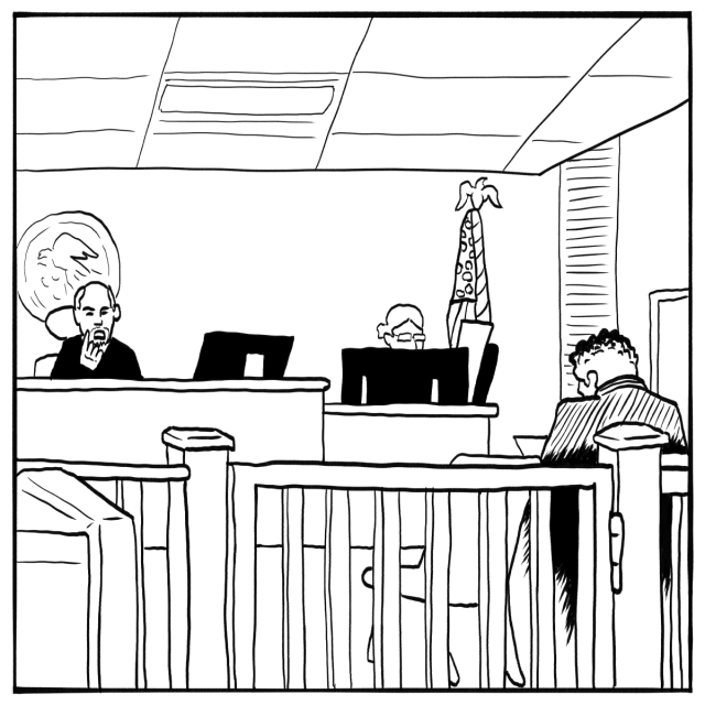 A courtroom scene with a judge seated at the bench, a person at a desk, and another individual sitting at a table in front of a wooden barrier.