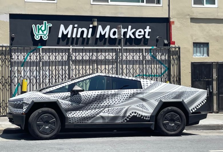 A geometric-patterned car with a futuristic design is parked on the street in front of a building with a "Mini Market" sign.
