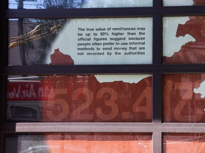 A sign on a window states that the true value of remittances may be up to 50% higher than official figures due to the use of informal money transfer methods.
