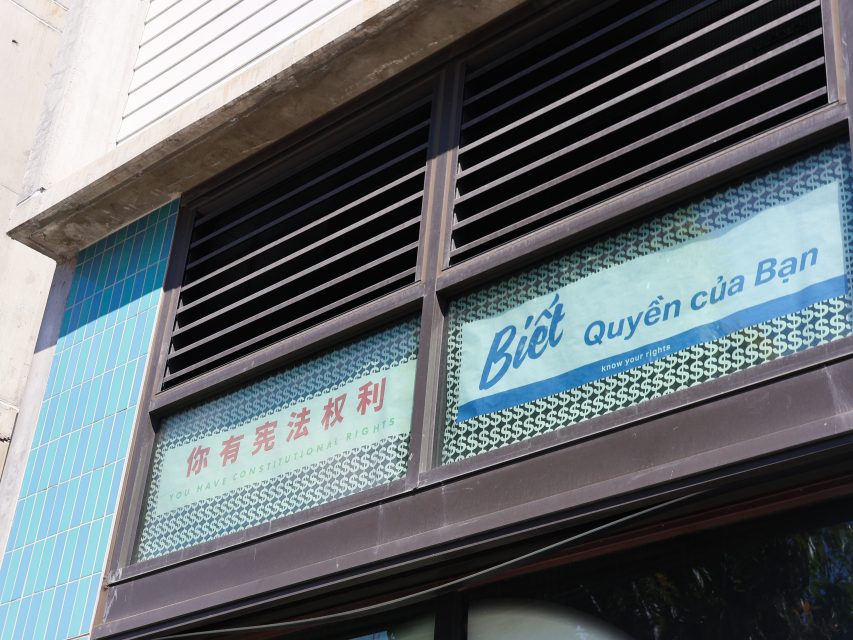 A building window displays signs reading “You Have Constitutional Rights” in Chinese, Vietnamese, and English.