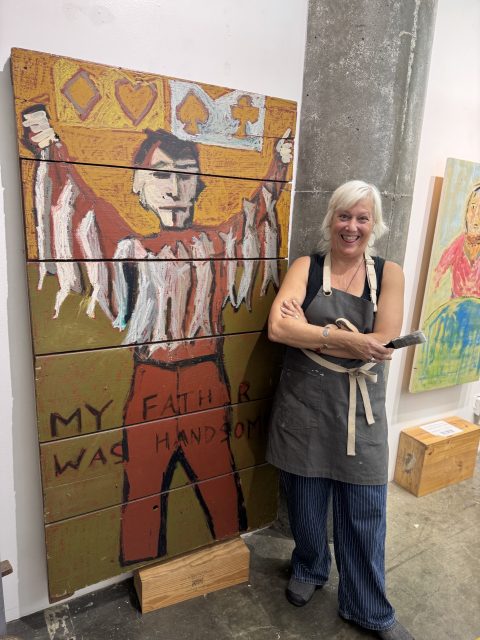 A woman standing next to a painting.