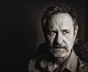 Black and white portrait of an older man with a beard, wearing a collared shirt, looking to the side with a serious expression.